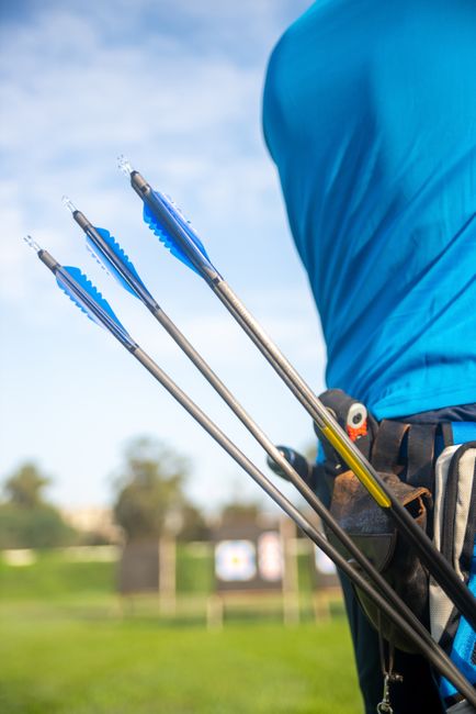 Three arrows in a quiver worn by an archer at an outdoor range. Perfect for sports and outdoor activity themes.