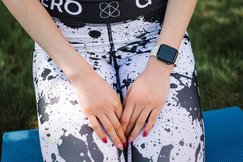 A smartwatch worn on a person's wrist with athletic leggings in an outdoor setting.
