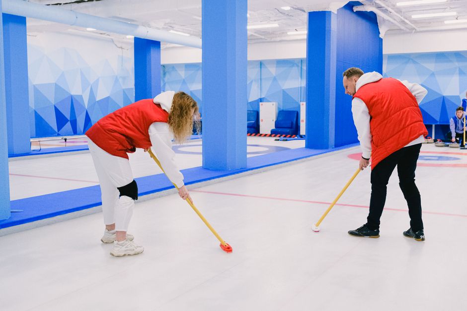 Male and female curlers with brooms sweeping smooth ice sheet during training on rink