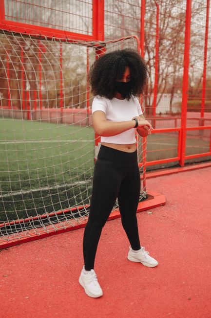Woman checking fitness tracker during outdoor workout in sports gear.