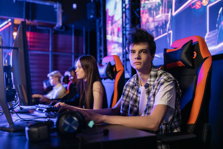 A group of teenagers intensely focused on a competitive gaming session in a vibrant esports arena.