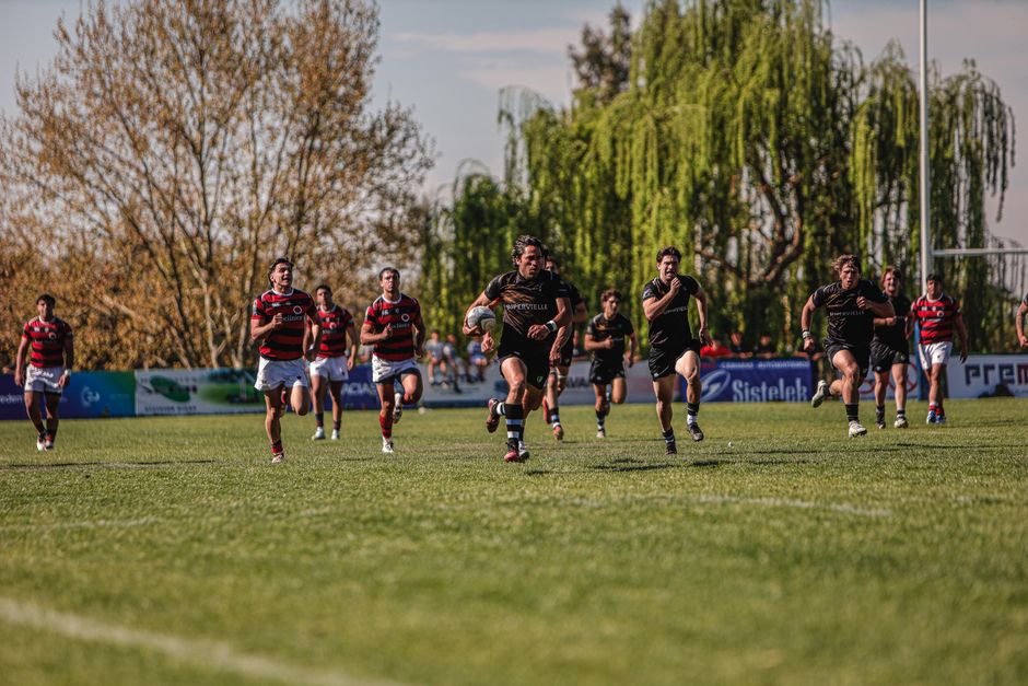 Rugby players sprinting on the field during a competitive match outdoors. Vibrant and dynamic sports scene.