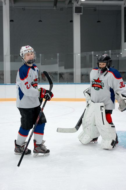 Young ice hockey players in gear on an indoor rink, preparing for a game.
