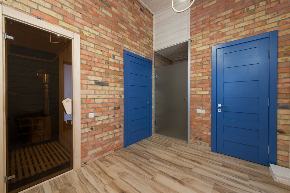 A stylish interior featuring blue doors, brick walls, and a sauna room in a cozy home setting.