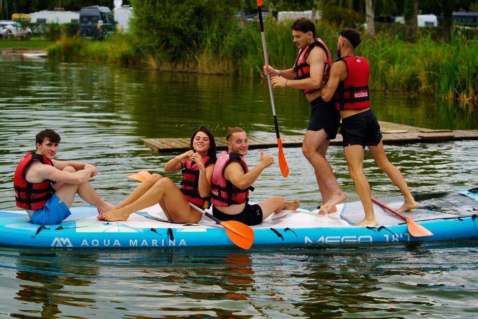 Young adults enjoying a fun paddle boarding adventure on a scenic lake.