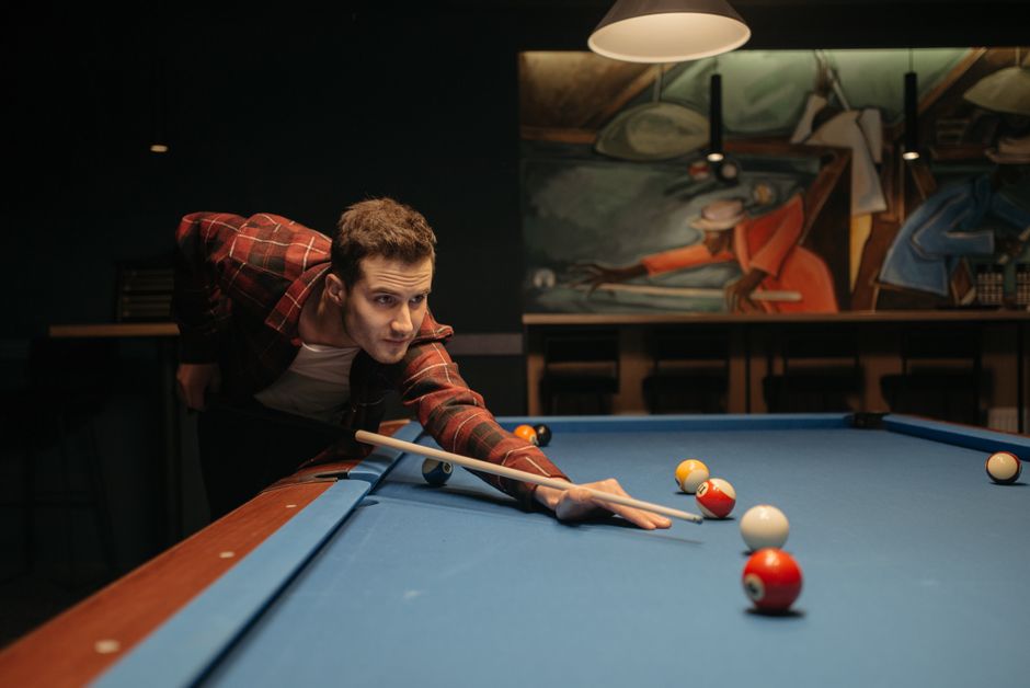A man concentrating while playing pool in a modern indoor setting.