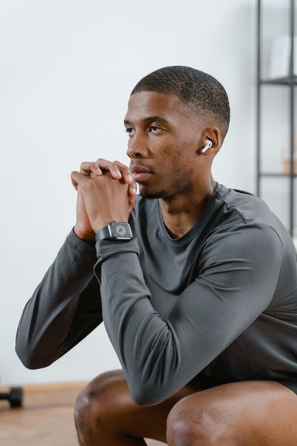 Young man in gray activewear focusing on his wellness during an indoor workout session.