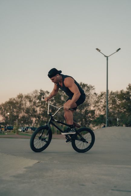 A skilled BMX cyclist executes a stunt in a Buenos Aires park during twilight.