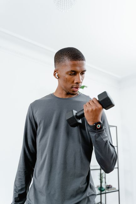 African American man lifting dumbbell indoors while exercising for fitness.