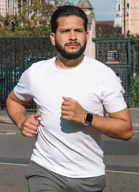Adult man jogging in London wearing casual athletic wear under sunny skies.