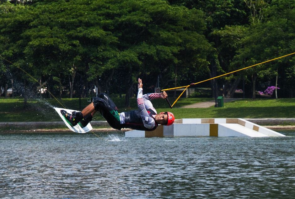Exciting action shot of a man performing a wakeboarding stunt at a cable park.