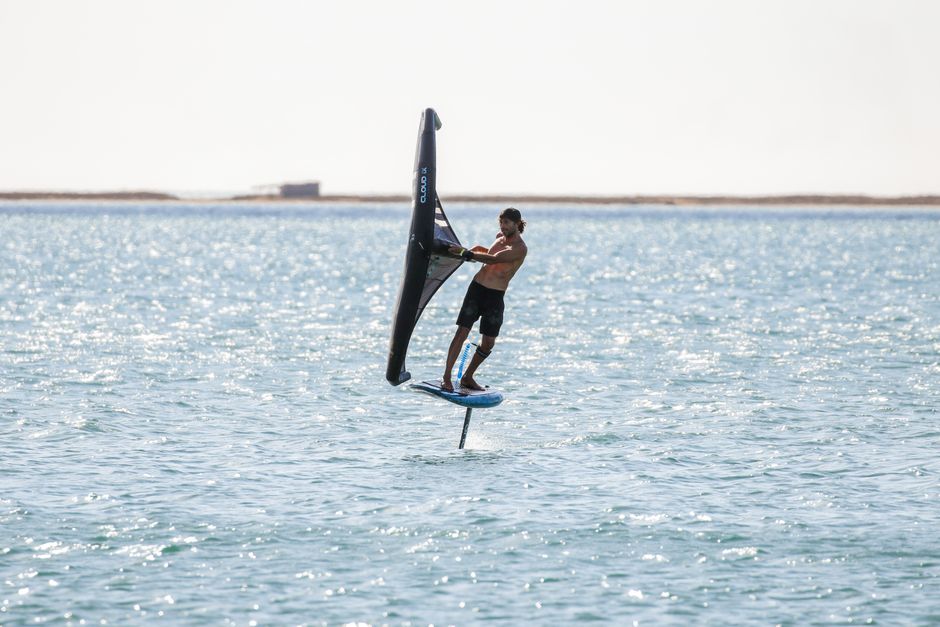 Man wing foiling on a sunny day, showcasing water sport excitement and skill.