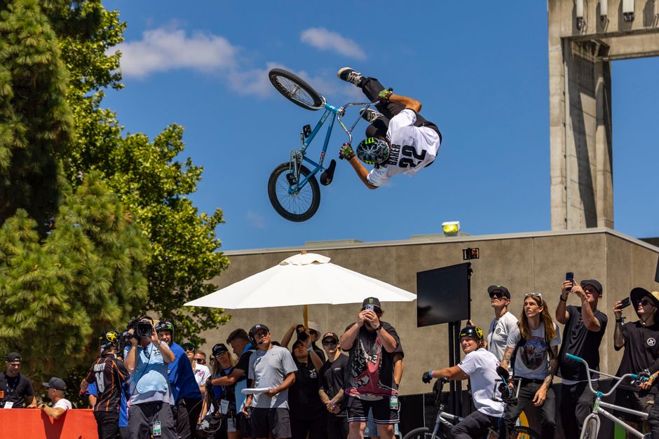 Thrilling BMX stunt performed in front of an excited outdoor crowd under clear skies.