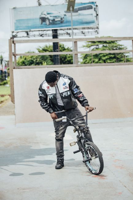 A young adult adjusting his BMX bike at a vibrant outdoor skate park area.