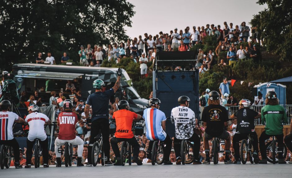 BMX riders gathered for an exciting competition with a cheering crowd in an outdoor urban setting.