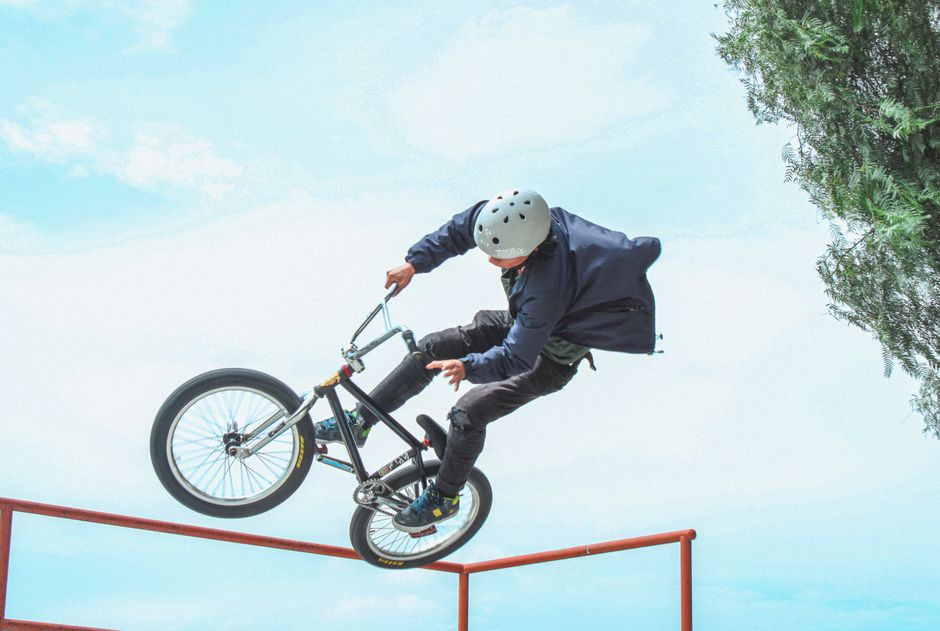 Thrilling BMX stunt captured mid-air in a sunny outdoor skatepark setting.