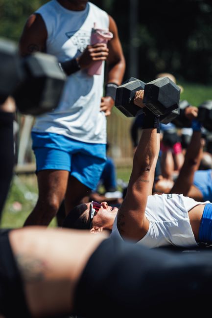 Group workout session with dumbbells at an outdoor fitness training event.