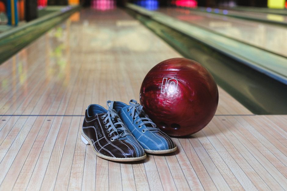 Bowling shoes and a red ball on a wooden lane, ready for action.