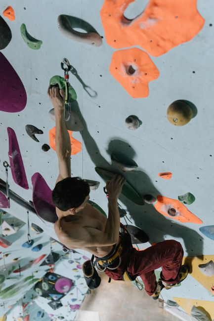 Athletic man practicing climbing on a vibrant indoor rock wall.