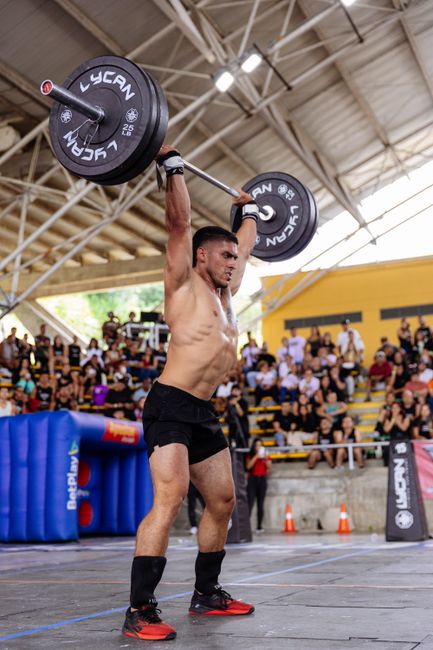 Male athlete lifting heavy barbell at indoor competition.