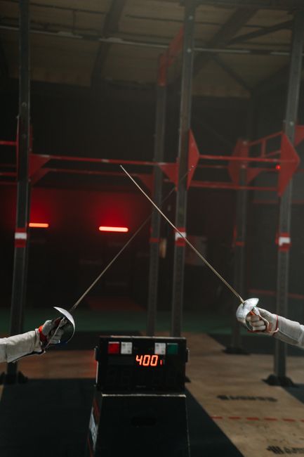 Two fencers engage in a duel with sabres. Sport timer displayed.