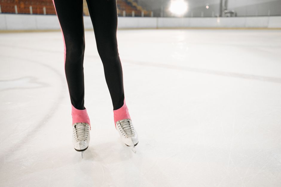 Detailed shot of ice skates gliding on an indoor rink.