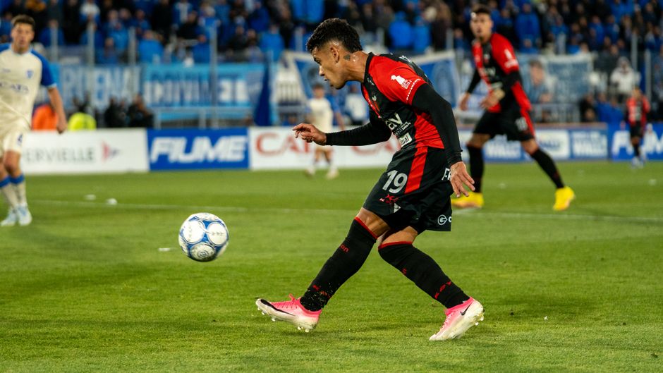 Dynamic capture of a soccer player in red and black uniform kicking the ball on the field.