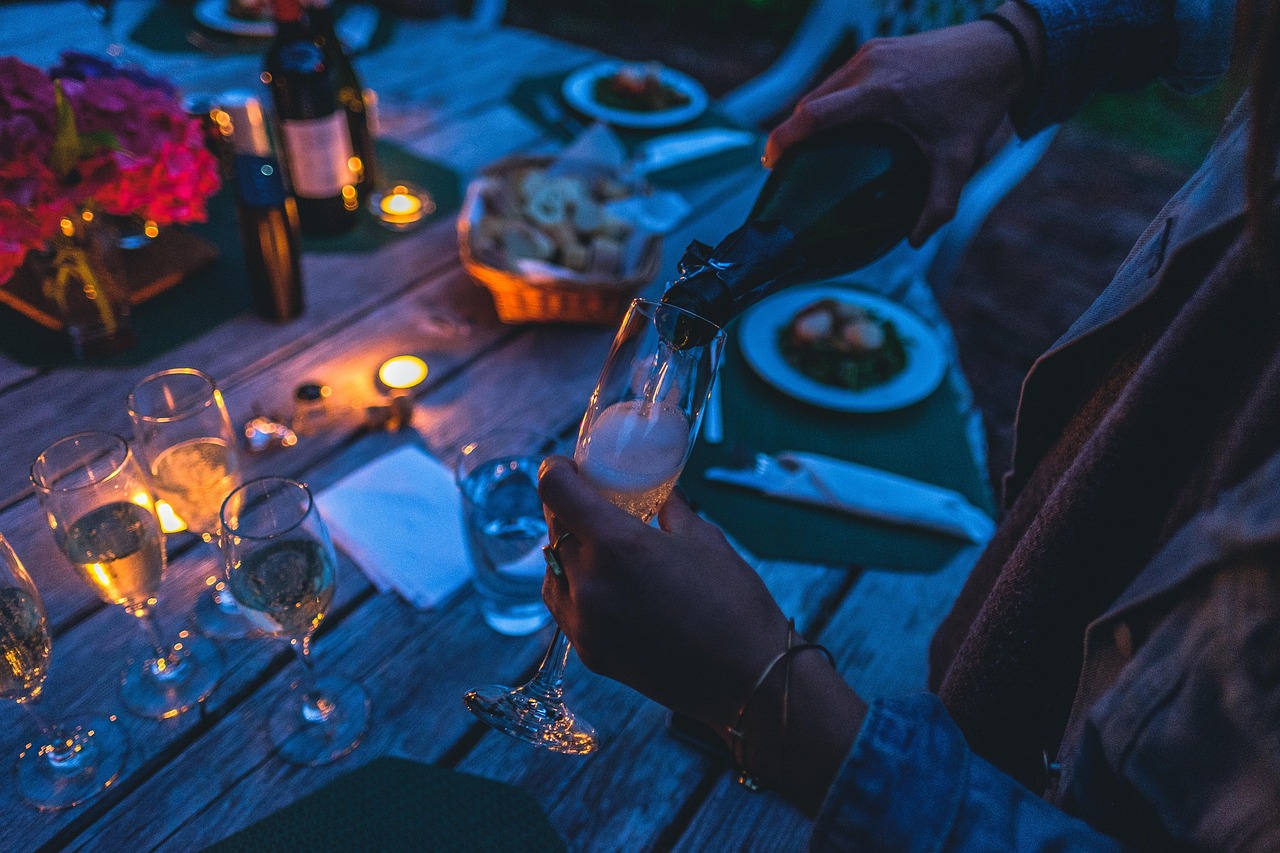 Celebration, champagne, glasses, pour, pouring, champagne glasses, bottle, champagne bottle, glassware, stemware, dark, dinner, evening, light, party, person, table, drinks, cheers, champagne, dinner,
