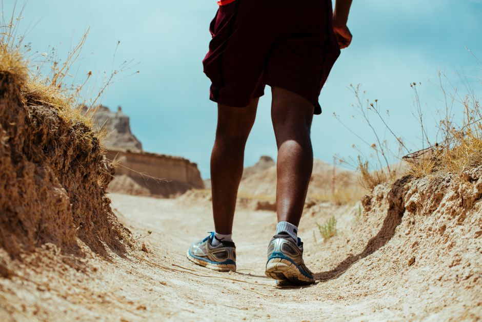 Person hiking through arid landscape wearing athletic gear on a sunny day.
