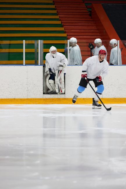Professional ice hockey players practicing on the rink indoors, showcasing teamwork and skills.