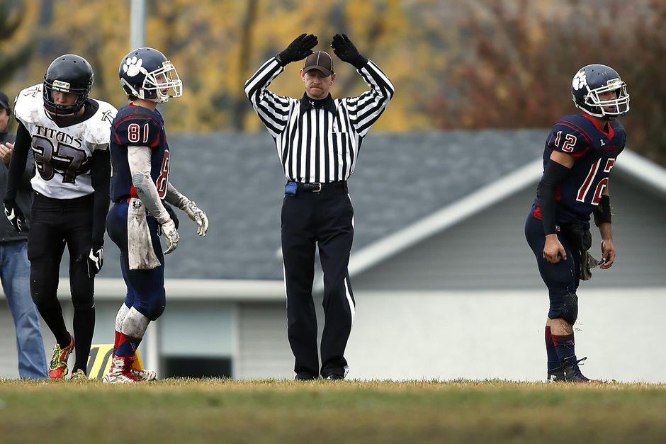 Referee calls timeout during intense high school football game outdoors.