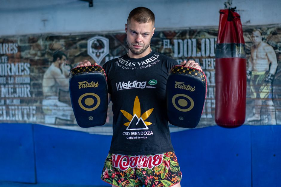 Kickboxer in gym holding training pads, showcasing martial arts attire.