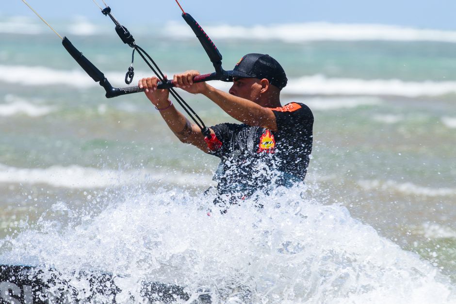 Energetic kitesurfer skillfully navigating ocean waves with splashes, showcasing extreme sports excitement.