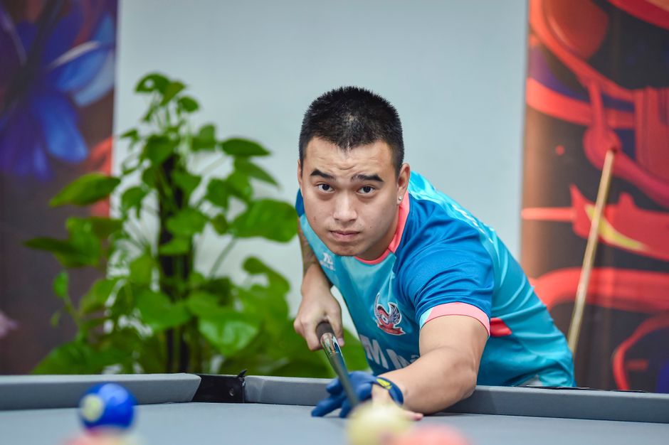 A determined billiards player lines up his shot in an indoor setting, showcasing skill and focus.