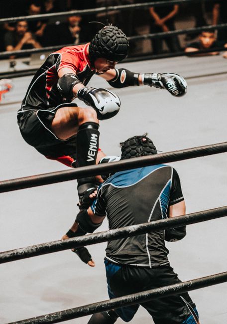 Two athletes engaged in a high-impact mixed martial arts competition, showcasing skill and agility.