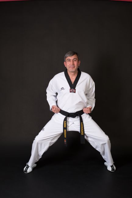 A martial artist performs a pose in a traditional uniform in a studio setting.