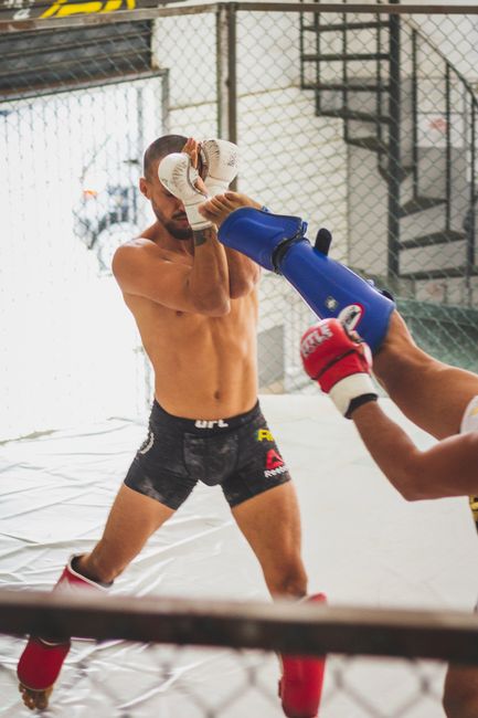 Two fighters sparring in an MMA gym, showcasing kickboxing techniques.