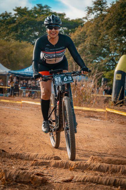 Woman cyclist competes in an outdoor mountain biking race amidst nature.