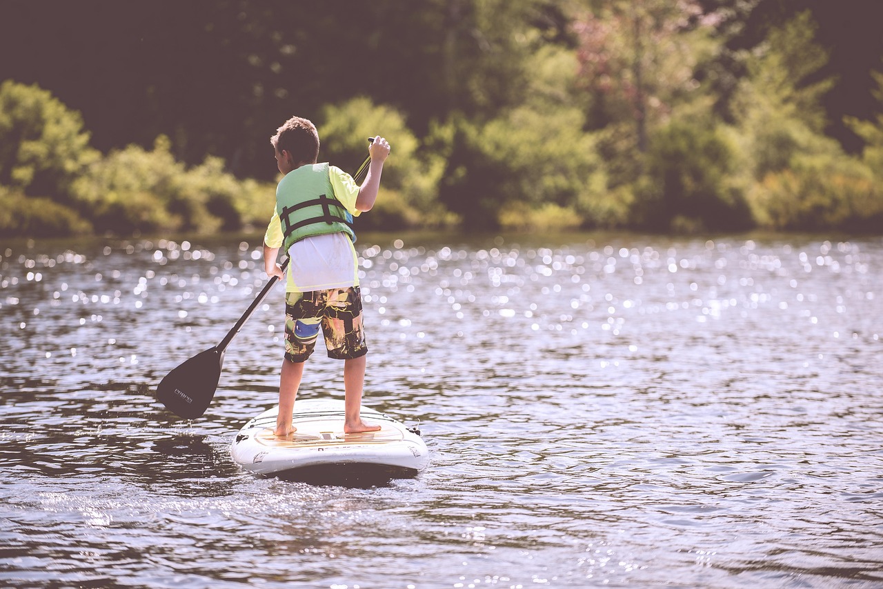 Boy, paddleboard, paddle, life jacket, pond, lake, paddleboarding, paddleboarder, child, fun, nature, kid, leisure, life vest, outdoors, person, recreation, river, surfboard, water, water sports