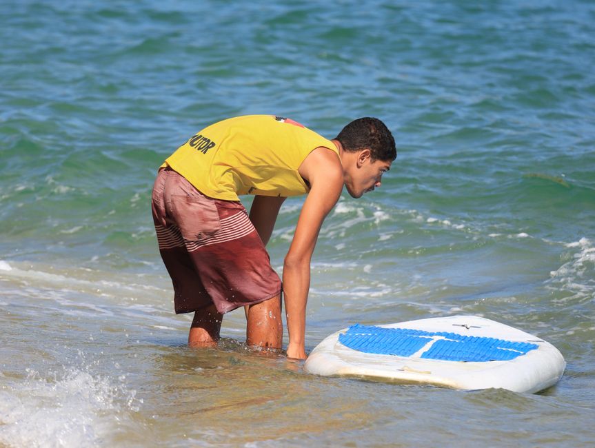 Young male setting up paddleboard at sunny beach, enjoying outdoor summer activity.