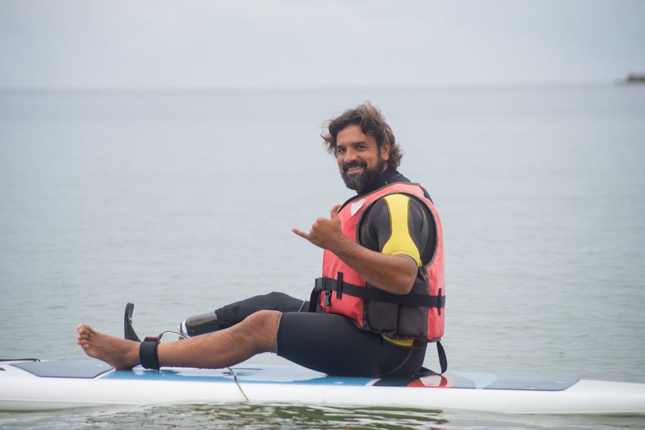 Man with prosthetic leg paddleboarding in Portugal's calm bay waters.