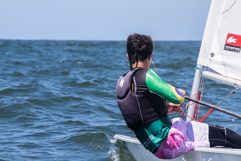 Back view of a young sailor navigating in a regatta on a sunny day.