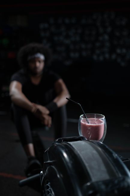 Strawberry smoothie with drinking straw in gym setting, perfect post-workout refreshment.