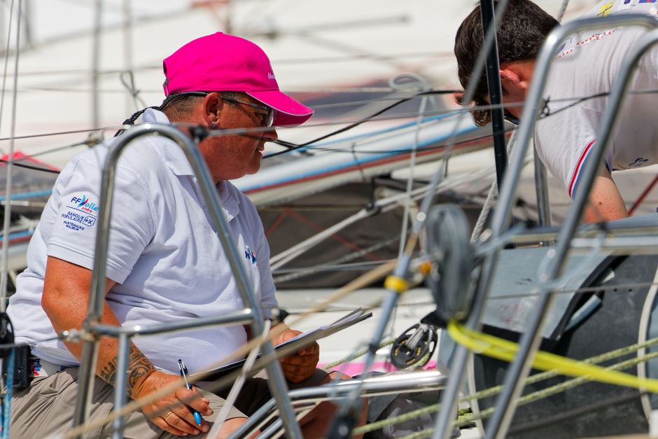 Sailing team discussing strategy aboard a yacht during a sunny day at sea.