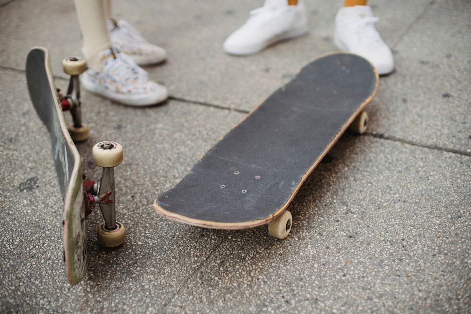 From above crop anonymous skaters wearing socks and gumshoes standing on city square near skateboards in daylight