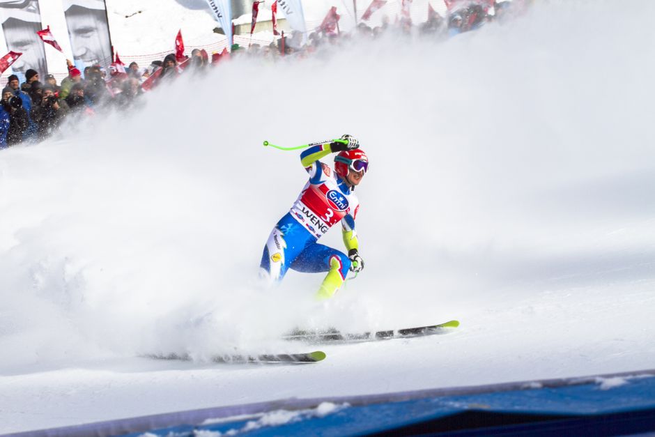 Intense ski race action captured with athlete carving through snowy slope in winter.