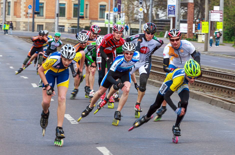 A group of athletes competes in a rollerblading race on urban streets, showcasing speed and endurance.