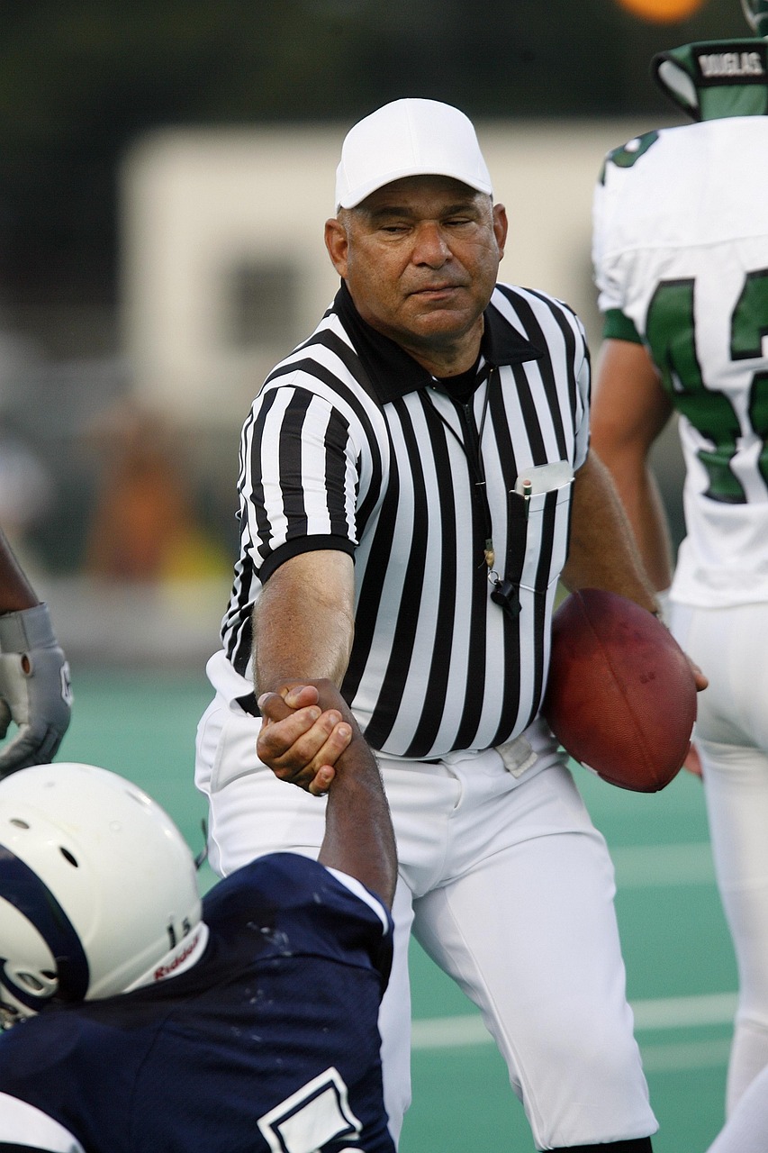 Referee, football, helping, lifting, lending a hand, official, sport, uniform, stripes, field, man, whistle, competition, judge, ball, decision, game, ref, stripped, male, player, rules, athlete, hat,