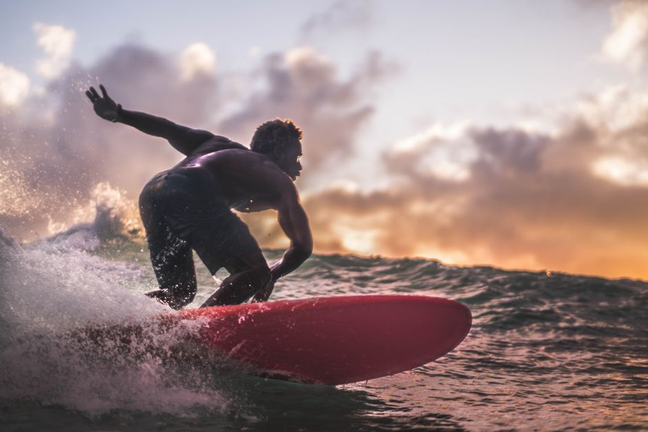 A surfer rides the waves during a vibrant sunset, showcasing an exhilarating ocean adventure.