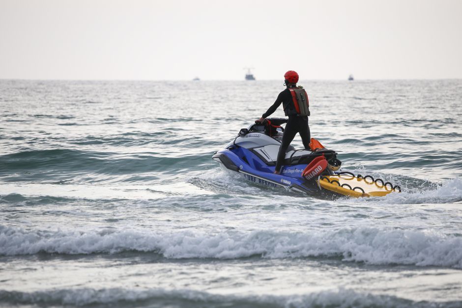 A lifeguard on a jet ski patrols the ocean to ensure swimmer safety during daytime.